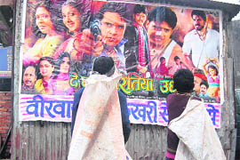 A couple of rag-pickers admire the poster of a movie in Dehradun on Tuesday.
