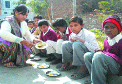 A primary schoolteacher serves mid-day meal to students in Nawanshahr.