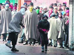 Youths pelt security personnel with stones during a protest in Srinagar on Wednesday. 