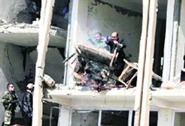 Afghan policemen throw out burnt furniture from the building, which was attacked by a suicide bomber in Kabul on Wednesday.