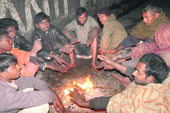 Labourers warm up around a bonfire in Dehradun on Thursday.
