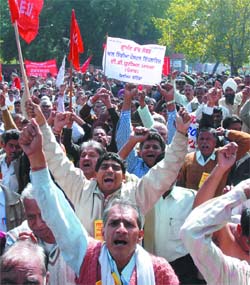 Postal workers under the banner of the All India Postal Employees Union demand immediate implementation of pay revision at Jantar Mantar in New Delhi on Friday.
