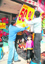 A shopkeeper puts up a discount banner in Jammu