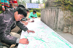 Youths draw trees in a banner at Gandhi Park, Dehradun, as part of Valentines Day celebrations