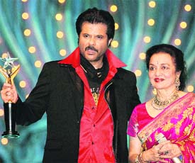 Bollywood actor Anil Kapoor (L) holds a special award for his film Slumdog Millionaire, after receiving it from actor Asha Parekh.
