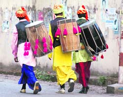 Three drummers look at election posters in Dehradun. 