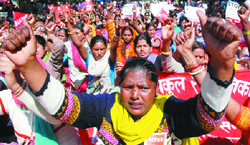 Employees under the All India Aganwadi Workers Federation demand recognition as full-time government employees in grade III and IV in New Delhi on Thursday.