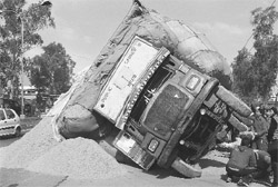 An overloaded truck carrying straw overturned while co-driver was fixing a jack for changing its punctured tyre in Ludhiana on Saturday.