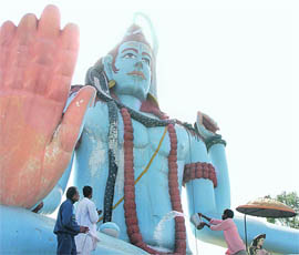 A devotee offers water on an idol of Lord Shiva on the Chandigarh-Ambala highway near Ambala on the eve of Shivratri on Sunday.