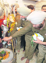 Uniformed policemen offer milk to Shivling at the famous Shivala Bhaian on the occasion of Mahashivratri in Amritsar on Monday.