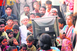 Neighbours of Azharuddin Ismail, who acted in Slumdog Millionaire, gather to watch the 81st Academy Awards presentation on television outside their homes in Mumbai. Ismail, along with the other cast members of the film, are in Los Angeles for the Oscars ceremony.