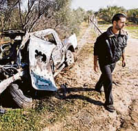 A Palestinian walks past a vehicle destroyed in an Israeli air raid on Gaza on Monday