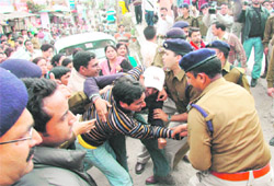 Police officials tackle contractual and visiting faculty lecturers outside the Uttarakhand Assembly on Tuesday.