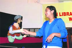 A student of Welham s shakes hands with a puppet at a show. 