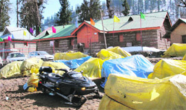 Snowmobiles lying under tarpaulin covers.