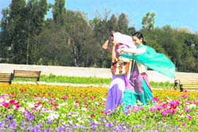 Two girls try to keep their dupatta in place at a park in Bhore camp in Jammu