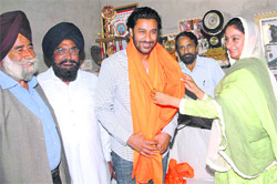 Punjabi singer Harbhajan Mann receives a siropa from Harsimrat Kaur Badal at his residence in Khemuwana village, Bathinda, on Friday.