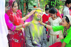 Students of Nanhi Duniya school apply colour to a foreigner in Dehradun on Monday.