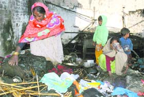 Relatives rummage through the burnt-up goods after a fire destroyed two houses in Karnal