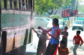 Children spray colours on a passing bus