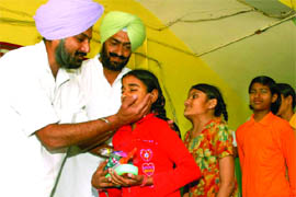 PPCC general secretary Raninder Singh presenting gifts to students of the deaf and dumb school in Bathinda on the occasion of Holi on Wednesday.