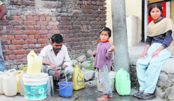 People fill their vessels on DL Road in Dehradun on Monday.