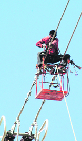 An electricity department employee works on high-tension wires on the Gurgaon-Mewat Road.