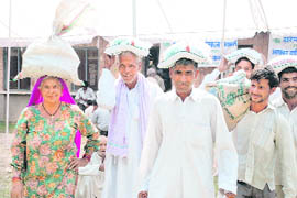Farmers carry bags of seeds purchased from stalls put up at Haryana Agricultural University in Hisar on Tuesday during the annual kisan mela. 