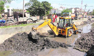 A JCB machine removes garbage from Ranbir Canal.