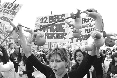 A demonstrator holds up dolls during a protest march in Nice, southeastern France, on Friday.