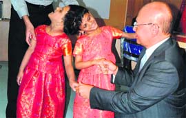 HELP AT HAND: Singaporean neurosurgeon Keith Goh greets conjoined twins Vani and Veena at the Niloufer Childrens Hospital in Hyderabad on Sunday. The unusual condition of the twins is known as Craniopagus, with the twins conjoined at the head and results in a risky separation operation. Doctor Goh, who has operated on four pairs of Craniopagus conjoined twins, and his team is to perform the cranial separation surgery for Vani and Veena along with Indian neurosurgeons in Singapore during August this year. 
