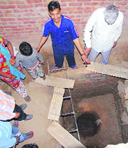 Residents show the septic tank where Pradeep fell to death in Nayagaon village on Monday.