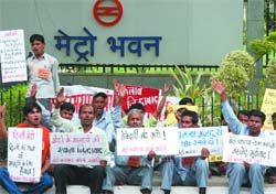 Workers of the Delhi Metro demonstrate outside the Metro Bhawan in New Delhi on Wednesday. They claimed they were not even paid the minimum wages guaranteed to them under the labour laws. 