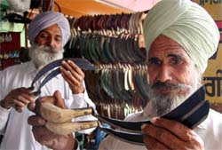 Ahead of the wheat harvesting season, farmers inspect the sharp edge of sickles at a hard-ware shop in Bathinda