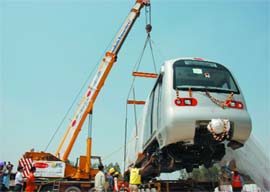 Delhi Metro staff unload a standard gauge metro train at Mundka Depot in New Delhi on Thursday. The train consists of two driving trailer and two motor coaches. It was shipped from South Korea last week.