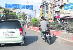 Youths on two-wheelers drive along the verge of the main Rajpur road. 