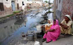 Women in Dhobiana Basti get their supply of drinking water amid the sewage. 