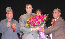 Yashpal Gupta, president of the Associated Chamber of Traders Federation and the Federation of Retailers Association, presents a bouquet to Chief Minister Omar Abdullah during a felicitation function at Jammu University on Friday. 