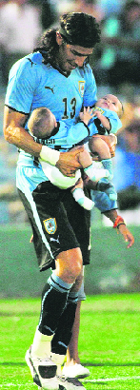 Uruguay's Sebastian Abreu carries his twin sons onto the field after they beat Paraguay in a World Cup qualifying soccer match on Saturday.