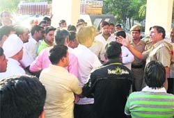 People gather at the Sector 56 police station after the firing incident in Gurgaon on Monday.