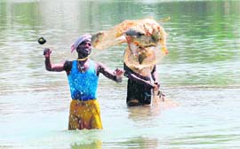 Two men catch fish in the Karan Lake in Karnal. 