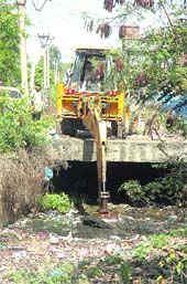 MC employees busy clearing the main drain in Nai Basti, Shastri Nagar, in Jammu on Monday. 