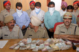 Police officials showing the money recovered from four persons, who enacted a fake robbery, during a press conference in Bathinda on Tuesday.