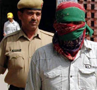 A policeman takes an accused in DLF loot case to a court in Gurgaon on Wednesday. 