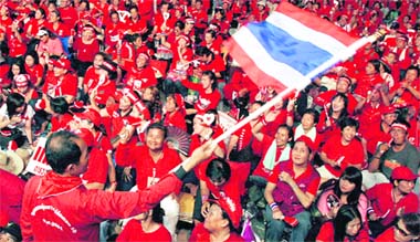 A supporters of former Thai Prime Minister Thaksin Shinawatra waves the flag of Thailand during an anti-government protest outside the Government House in Bangkok on Wednesday. The Thai government has offered to negotiate with the exiled Prime Minister to end a week-long street campaign, threatening its efforts to stave off an economic recession. 