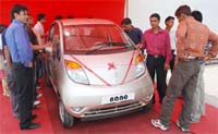 People look at a Nano car at a showroom in Gurgaon