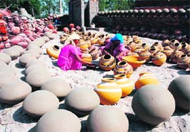 Two women give the finishing touches to earthen pots at Assandh in Karnal district