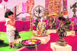 A little girl prays before the idols of goddesses at an exhibition in Dehradun on Monday. 