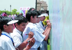 Students sign a billboard during a signature campaign on health to mark the World Health Day, at the India Gate in New Delhi 