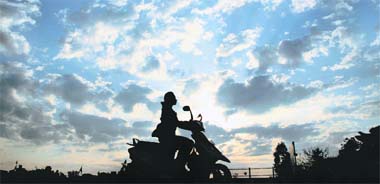 A girl enjoys her ride as she returns home amidst a cloudy sky in Jammu